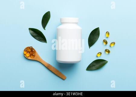 Les capsules Omega-3 se trouvent dans une bouteille blanche sur une table avec un fond de feuilles vertes. Comprimés d'huile de poisson. Additifs biologiquement actifs. omega 6, omega 9, vitam Banque D'Images