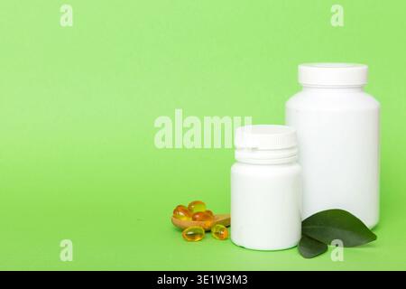Les capsules Omega-3 se trouvent dans une bouteille blanche sur une table avec un fond de feuilles vertes. Comprimés d'huile de poisson. Additifs biologiquement actifs. omega 6, omega 9, vitam Banque D'Images