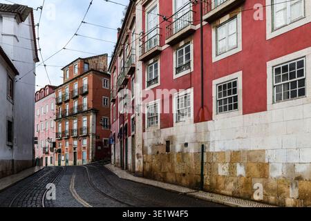 Rue pavée étroite à Lisbonne, Portugal bordée de vieux bâtiments colorés dans le quartier historique d'Alfama. Banque D'Images