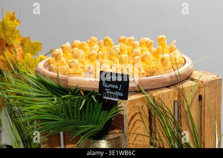Gros plan de feuilletés au fromage (gougères) disposés sur un présentoir rustique en bois, servis comme hors-d'œuvre pour un événement ou un buffet. Banque D'Images