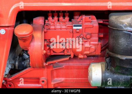 Un gros plan montre le bloc moteur rouge et l'ensemble pompe à carburant d'un tracteur illustrant des machines agricoles ou industrielles. L'image est mise en surbrillance Banque D'Images