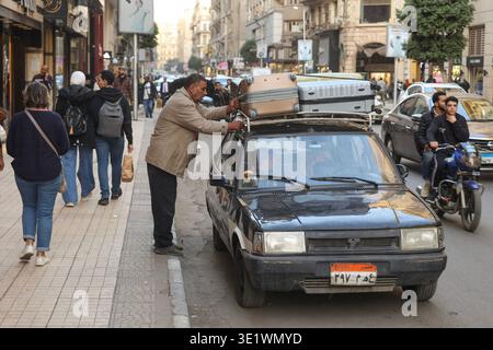 Le Caire, Egypte - 12232024 - scène de rue animée dans le centre du Caire, Egypte, avec une voiture garée étant chargée sur le trottoir, des piétons marchant le long du flanc Banque D'Images