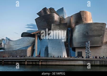 Le musée Guggenheim Bilbao, conçu par Frank Gehry, présente ses courbes emblématiques revêtues de titane sous un ciel bleu vif près de la rivière Nervion. Espagne. Banque D'Images