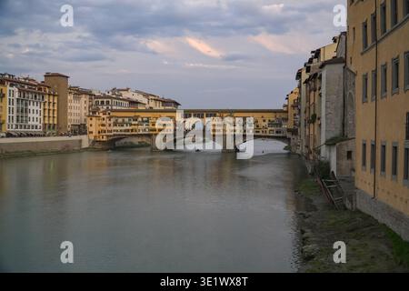 Ponte Vecchio, Ponte Vecchio. Florence, Italie. Pont médiéval emblématique connu pour ses boutiques, construit en 1345. Scène de rivière crépusculaire avec petit bateau. Banque D'Images