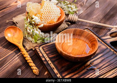 Des fleurs parfumées fleurissent sur un arbre, attirant les abeilles pour le nectar. Le miel est recueilli dans des bols placés sur une table en bois. La scène montre l'activité printanière Banque D'Images