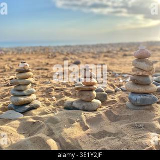 Pierres empilées équilibrées sur la plage de sable avec fond d'océan doux et faible profondeur de champ Banque D'Images