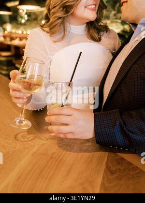 Couple profitant de boissons dans un bar lors d'une soirée décontractée avec un éclairage chaleureux et une ambiance cosy Banque D'Images