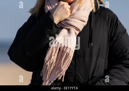 Foulard rose doux avec manteau d'hiver noir pour adultes en extérieur, détail de garde-robe saisonnier pour la vente de mode, le confort et les thèmes de la saison froide Banque D'Images