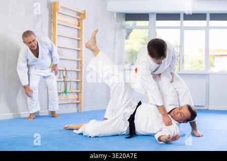 Jeune homme travaillant sur les compétences en arts martiaux dans la lutte d'entraînement avec rival masculin Banque D'Images