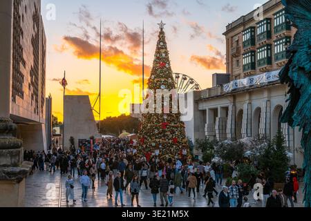 La Valette, Malte - 25 décembre 2025 : des foules festives se rassemblent autour de l'arbre de Noël géant à Triton Square, la Valette, Malte au coucher du soleil Banque D'Images