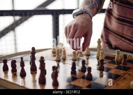 Jeune homme adulte jouant aux échecs faire un mouvement stratégique Banque D'Images