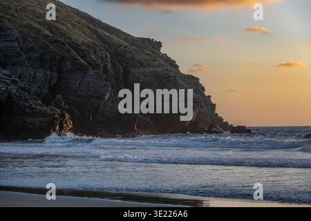 Falaises côtières au coucher du soleil avec des vagues qui s'écrasent et des reflets de ciel doré sur l'eau. Todos Santos, basse Californie, Mexique Banque D'Images