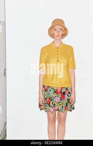 Femme en haut jaune et jupe florale, portant un chapeau de paille sur un fond blanc. Allemagne Banque D'Images