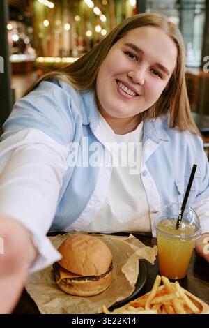 Portrait de jeune femme adulte souriant tout en prenant Selfie au Café Banque D'Images