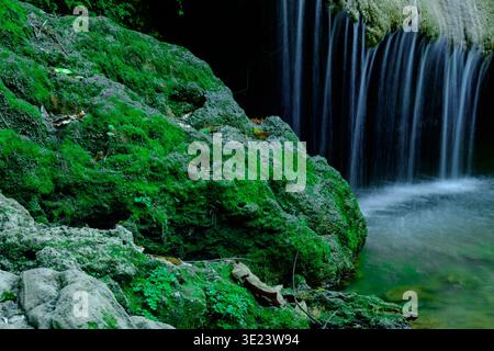 Cascade douce coulant sur des roches moussues vibrantes, exprimant la tranquillité, la pureté naturelle, le calme émotionnel, le renouvellement, et connexion paisible avec untouch Banque D'Images