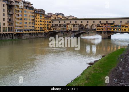 Le pont historique du Ponte Vecchio, bordé de boutiques, enjambe le fleuve Arno sous un ciel nuageux à Florence, en Italie Banque D'Images
