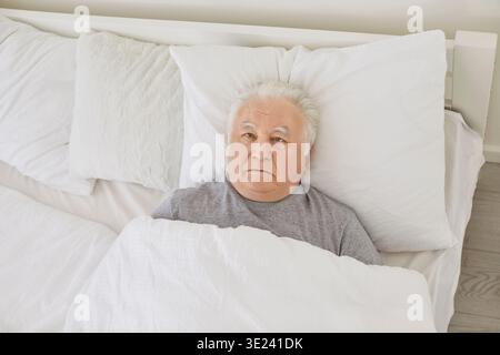 Homme âgé atteint de troubles du sommeil insomniques couché dans son lit regardant le plafond Banque D'Images