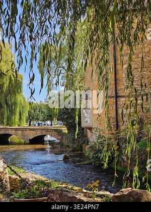 Une vue encadrée depuis le Cotswold Motoring Museum donne sur un pont sur la rivière Windrush à Bourton-on-the-Water. Banque D'Images