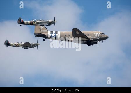 Headcorn Battle of Britain Airshow - C-47 Dakota historique de la seconde Guerre mondiale volant en formation avec deux Supermarine Spitfires au-dessus du ciel bleu pendant un vol Banque D'Images