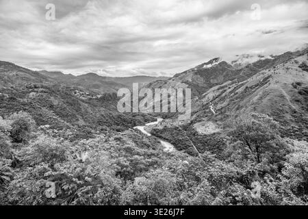 Coban, Guatemala - Une scène spectaculaire de vallée de montagne monochrome avec une rivière sinueuse coupant à travers une végétation dense et des collines ondulantes sous Clo sombre Banque D'Images