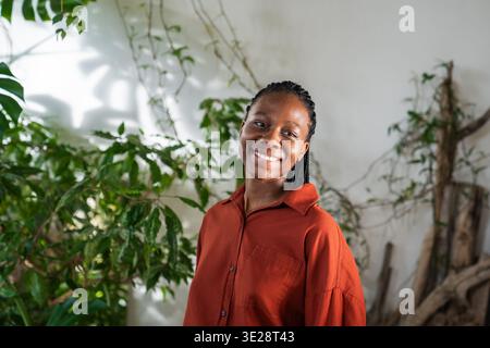 Femme afro-américaine confiante positive dans le jardin à la maison avec une expression optimiste souriante. Banque D'Images