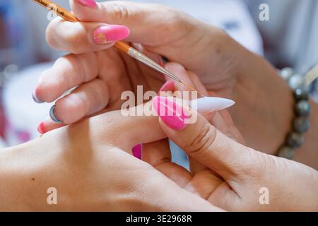 Du haut de la récolte méconnaissable manucure faisant nail art pour la cliente féminine dans le salon de beauté Banque D'Images
