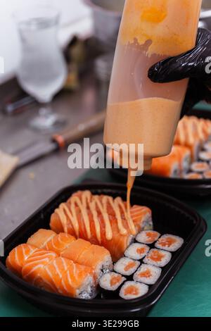 Sauce du chef arrosante sur rouleaux de saumon avec bouteille pressée, Mayo épicée crémeuse appliquée en finition Banque D'Images