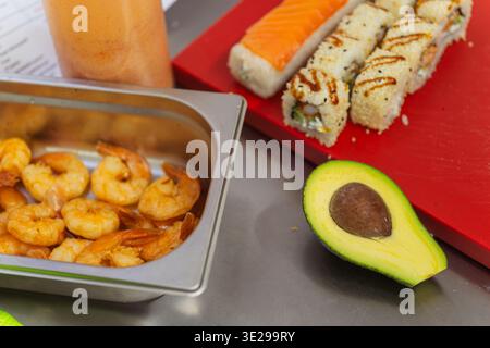 Plateau de crevettes cuites à côté de Sushi et avocat, mise en scène des ingrédients pour le service dans le restaurant Sushi Banque D'Images