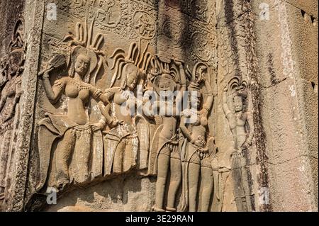 Thème de l'art historique montrant en gros plan les détails de la sculpture traditionnelle khmère en pierre des déesses féminines sur la façade altérée du monument religieux dans tro Banque D'Images