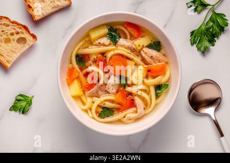 Soupe au poulet avec nouilles et légumes dans un bol blanc Banque D'Images