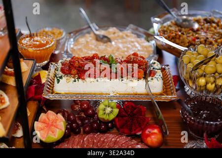 Buffet de mariage élégant avec fromage blanc et confit de tomates cerises. Composition avec des fruits de dragon, kiwi, raisins, et assortiment de viandes pour Banque D'Images