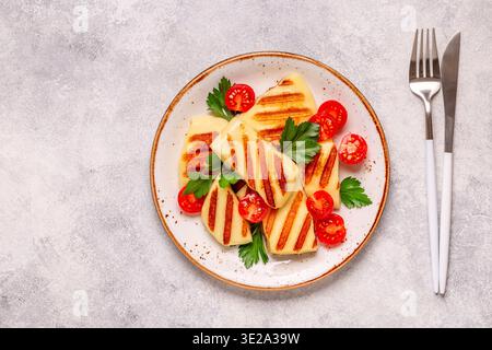 Fromage halloumi grillé servi avec des tomates et du persil. Banque D'Images