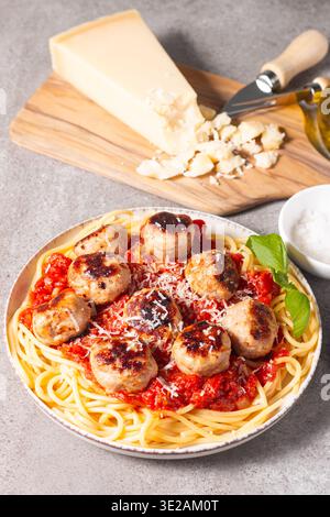 Une assiette de spaghettis classiques garnie de boulettes de viande dorées et d'une riche sauce tomate sur un plat en céramique légère. Banque D'Images