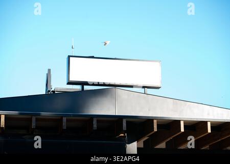 Panneau d'affichage vierge sur le toit d'un bâtiment contre un ciel bleu clair Banque D'Images