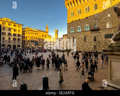 Les gens marchent sur la Piazza Della Signoria, une place populaire de Florence, alors que le soleil d'hiver de fin d'après-midi se couche à Florence, en Italie Banque D'Images