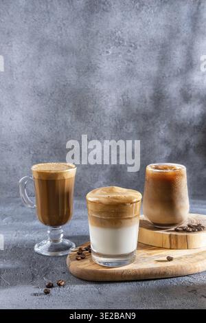 Café glacé dans un grand verre avec de la crème versée sur et des grains de café. Set avec différents types de boissons au café sur une table sombre Banque D'Images