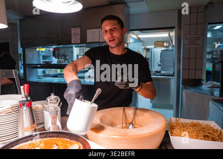 Chef remue des pâtes dans la roue Parmigiano Reggiano à Oberlech, Autriche Banque D'Images