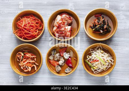 Cuisine coréenne - vue de dessus de divers plats d'accompagnement (banchan ou panchan) dans des bols en céramique sur la table grise Banque D'Images