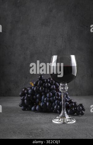 Verre de vin rouge avec fromage bleu et raisins sur fond sombre. Vin rouge avec fromage et fruits. Espace pour le texte Banque D'Images