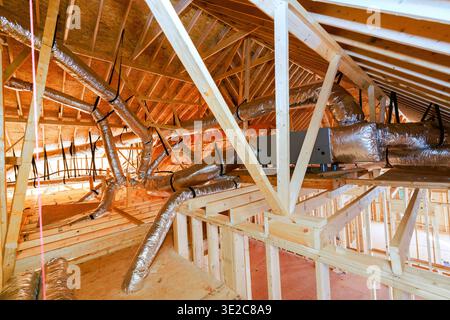 Les ouvriers installent des conduits d'air dans l'espace grenier de la nouvelle maison en construction Banque D'Images