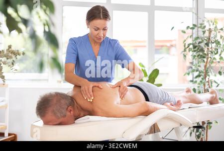 masseuse donnant massage à un patient masculin Banque D'Images