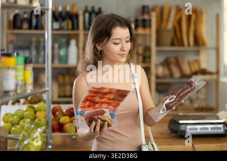 La jeune femme choisit la viande séchée en magasin Banque D'Images