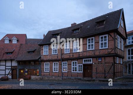 Rangée de maisons traditionnelles en briques à ossature de bois avec des toits en tuiles abruptes et des fenêtres blanches sur une rue pavée sous un ciel nuageux du soir dans un charme Banque D'Images
