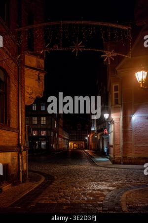 Moody Night vue sur une rue pavée étroite avec des bâtiments historiques des lampadaires chauds et des arches de lumière décoratives créant une vieille ville atmosphérique Banque D'Images