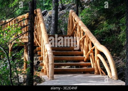 Escalier en bois avec des mains courantes sculptées dans une zone montagneuse boisée au nord de la Carélie. Banque D'Images