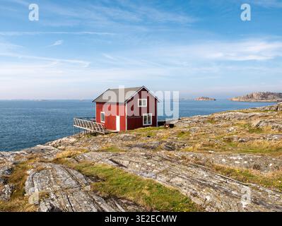 Maison en bois rouge sur la côte rocheuse à Åstol, Bohuslän, côte ouest de la Suède, avec mer ouverte et îles Banque D'Images