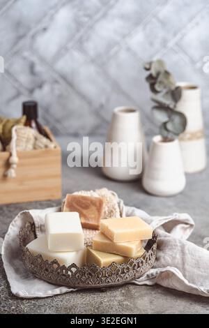 Savons divers et accessoires de bain sur une plaque métallique sur fond gris, verticale avec espace copie Banque D'Images