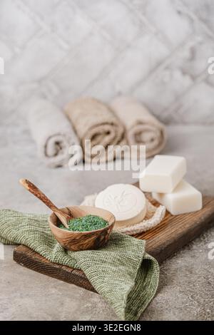 Savons divers, sels de bain et accessoires de bain sur fond bois et gris, vertical avec espace copie Banque D'Images