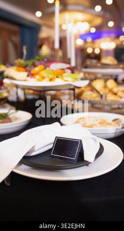 Une table de buffet magnifiquement agencée avec des plats gastronomiques, des fruits frais et des accents floraux sous un éclairage ambiant chaleureux. Parfait pour réception de mariage Banque D'Images