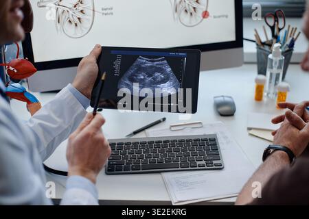 Urologue caucasien d'âge moyen expliquant les résultats de l'échographie au patient Banque D'Images